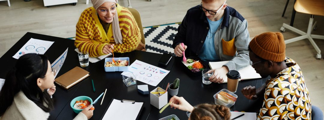 High angle view at diverse creative team at coworking space during lunch